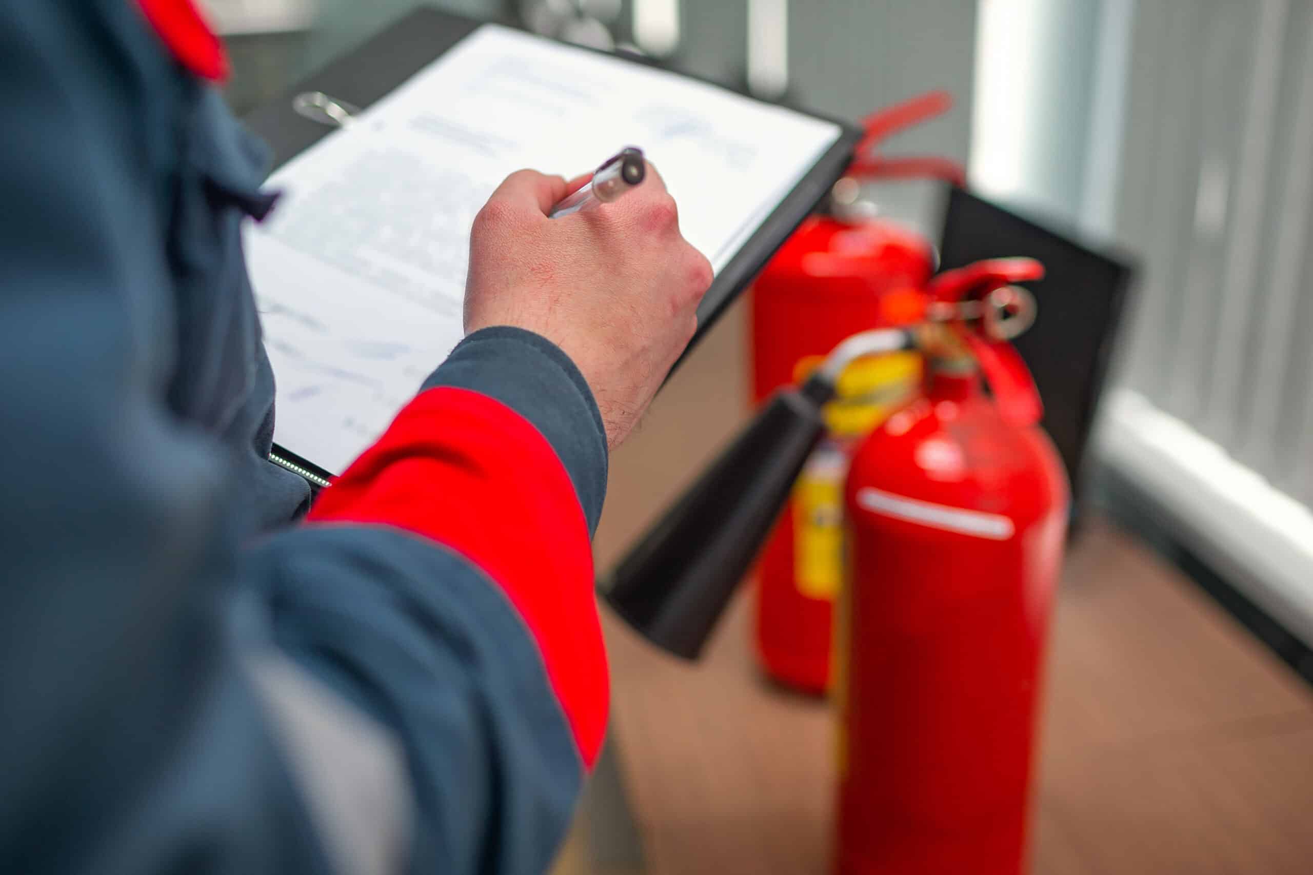 Professional Fire Safety engineering checking fire extinguishers using a clipboard.